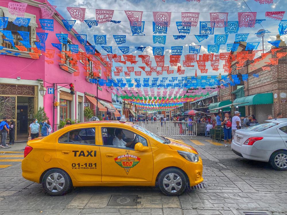 Yellow taxi on a Oaxaca street decorated with papel picado